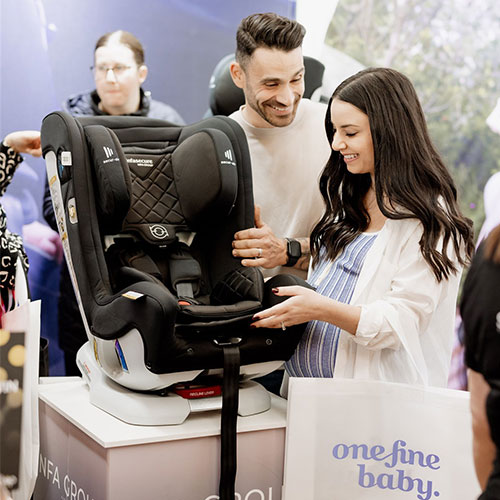 Pregnant woman and her partner at the Baby Expo in Sydney, selecting baby car seats for their upcoming arrival.