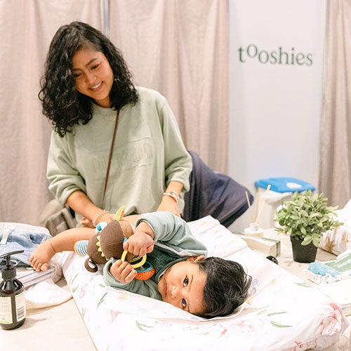 Mum changing her baby's nappy in the Tooshies parents' room at the Baby Expo in Sydney.