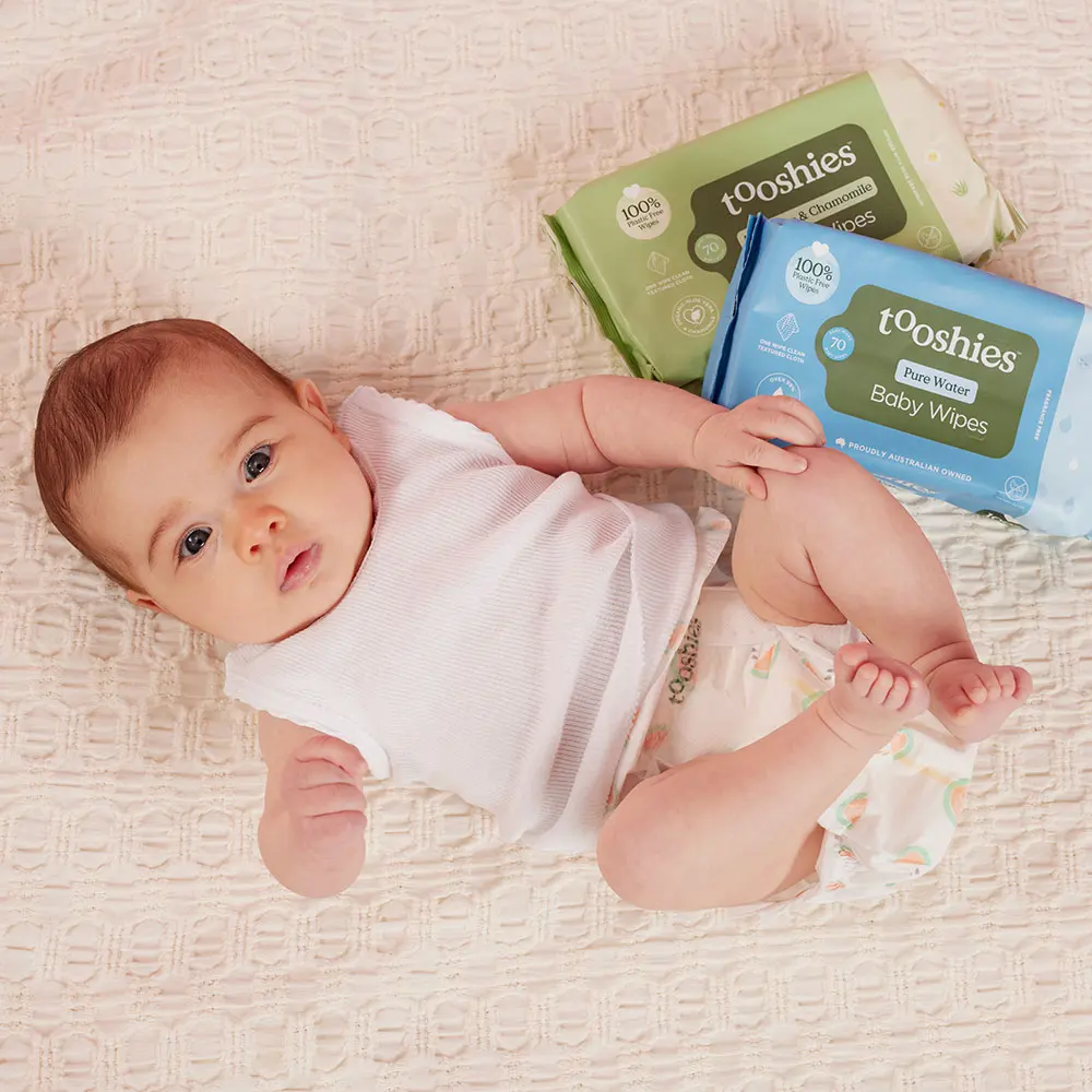 Smiling baby next to a stack of Tooshies nappies on display at the Sydney baby expo.